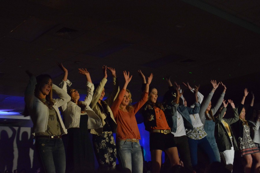 Senior girls raise their arms up for a picture. 