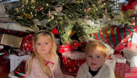Two children under a Christmas tree surrounded by presents on Christmas morning