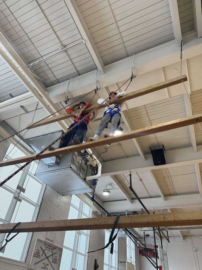 Sonny Liranzo 26 and Colin Peterson 26 reach the top of the high beam element while peer leaders belay, making the obstacle as safe as possible.