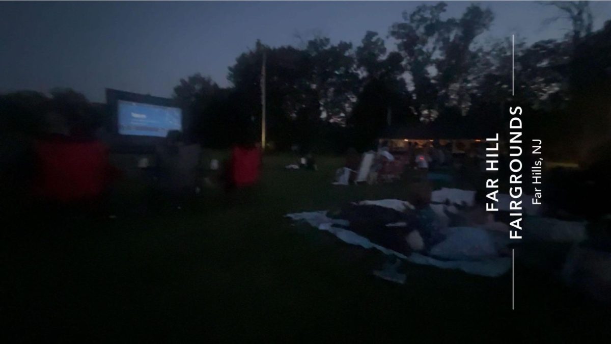 Movie-watchers sit on blankets while watching ET