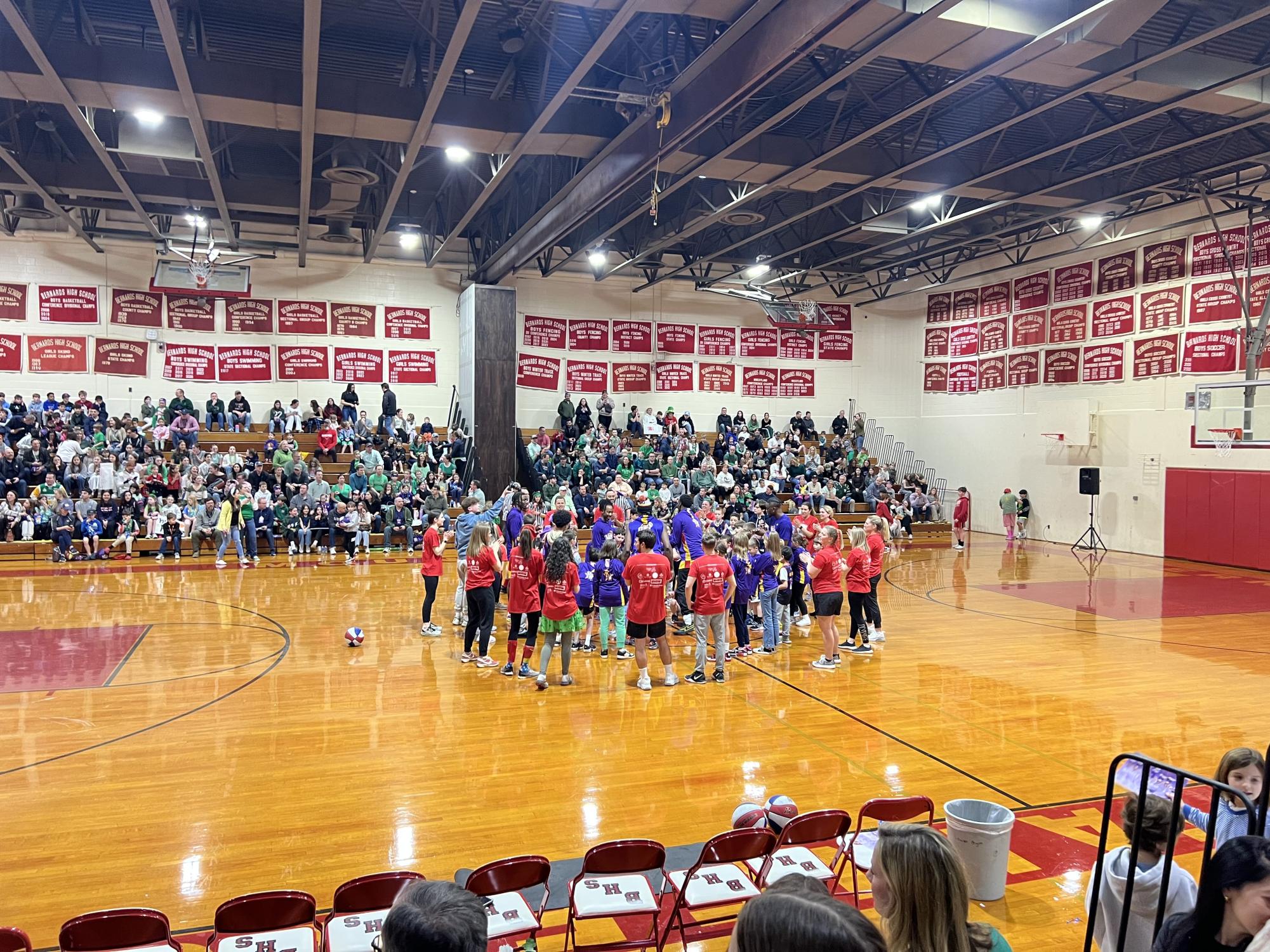 The faculty team and wiz kids standing in a circle around the Harlem Wizard performers