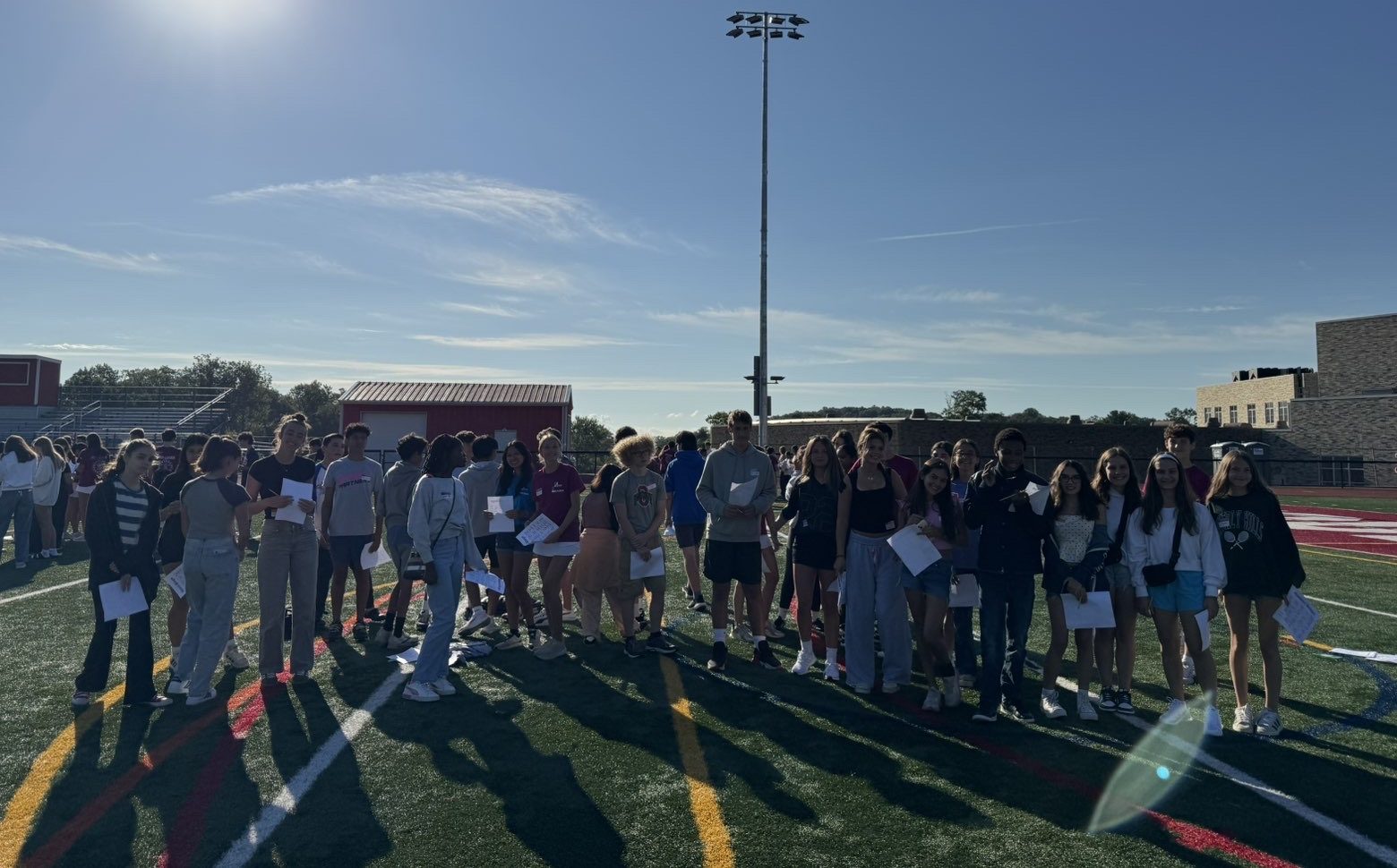  Freshman poses on the turf with the Peer Leaders at orientation